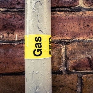 detail of a residential gas pipe against a red brick wall