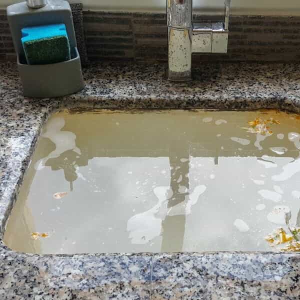 close-up of an overflowing kitchen sink with a clogged drain